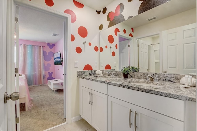 bathroom featuring a sink, visible vents, double vanity, and tile patterned flooring