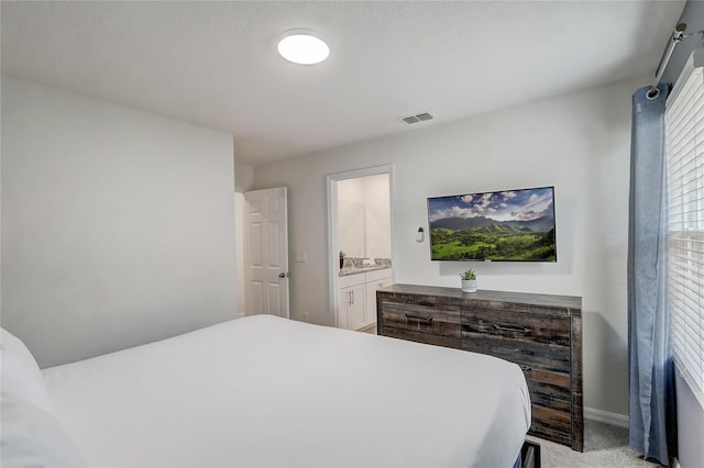 bedroom with visible vents, baseboards, light colored carpet, and connected bathroom