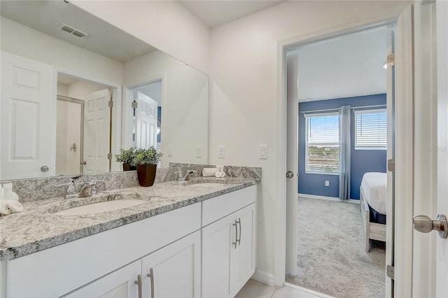 ensuite bathroom featuring double vanity, visible vents, baseboards, and a sink