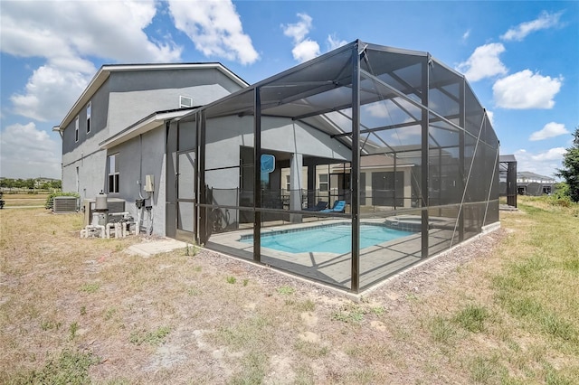 back of property with a yard, central AC, stucco siding, a lanai, and a patio area