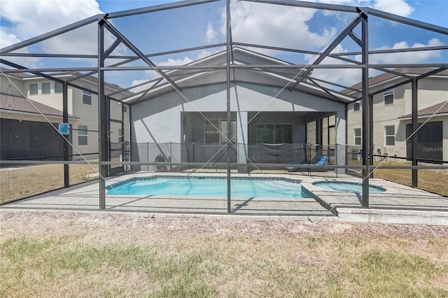 pool featuring glass enclosure, a patio, and an in ground hot tub