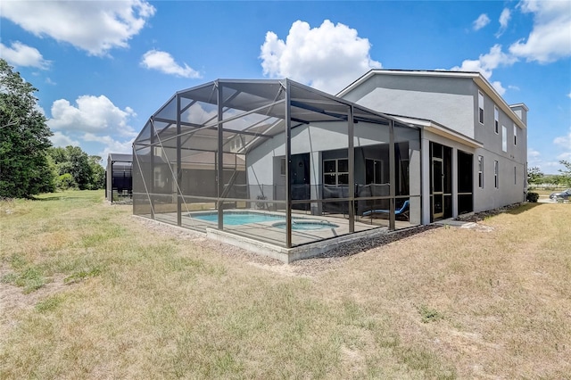 back of house with glass enclosure, a lawn, an outdoor pool, and stucco siding