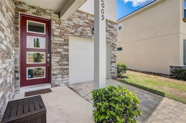 property entrance featuring a garage, stone siding, and stucco siding