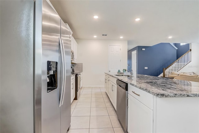 kitchen with white cabinetry, sink, stainless steel appliances, light stone counters, and light tile patterned flooring