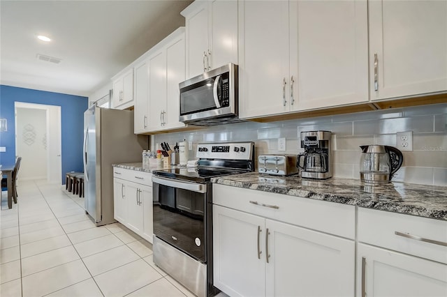 kitchen with light stone countertops, backsplash, white cabinetry, and stainless steel appliances