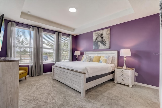 bedroom with a tray ceiling, carpet floors, and baseboards