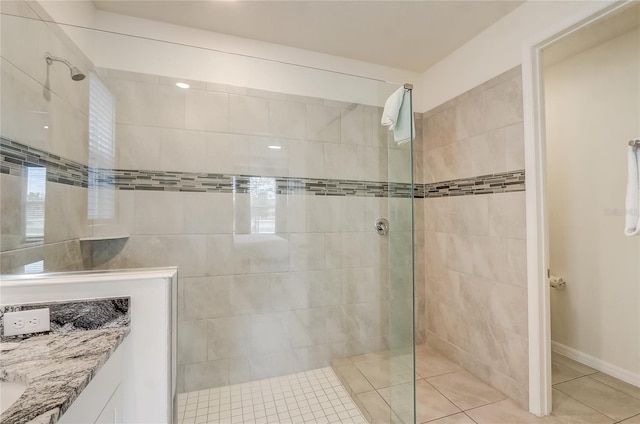 bathroom with tiled shower, vanity, and tile patterned floors