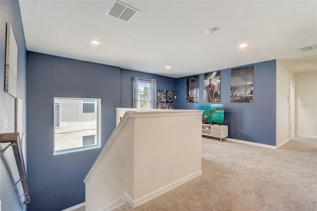 hall featuring an upstairs landing, visible vents, baseboards, and carpet floors