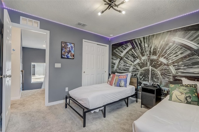 bedroom with a textured ceiling, baseboards, visible vents, and light carpet