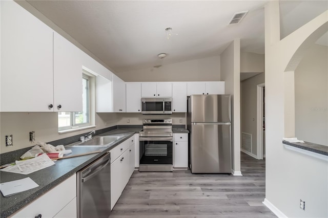 kitchen featuring white cabinetry, sink, stainless steel appliances, light hardwood / wood-style flooring, and lofted ceiling