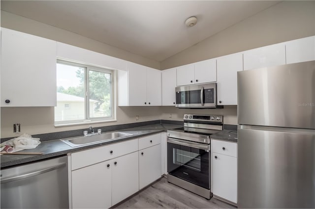 kitchen with white cabinetry, sink, stainless steel appliances, lofted ceiling, and light wood-type flooring