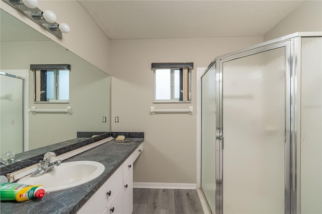 bathroom with vanity, wood-type flooring, a textured ceiling, and a shower with door