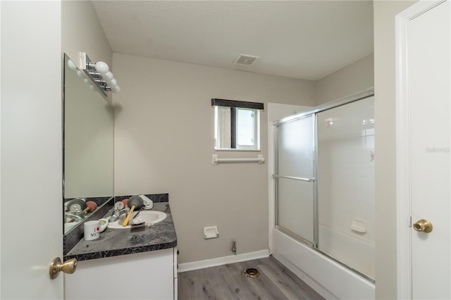 bathroom with hardwood / wood-style flooring, vanity, and bath / shower combo with glass door