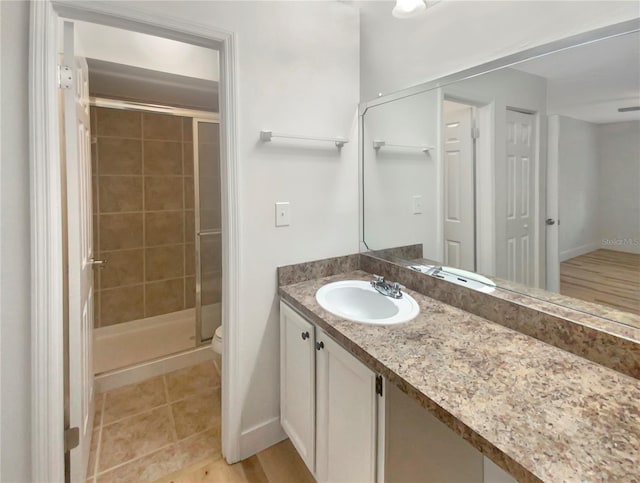 bathroom with tile patterned floors, vanity, toilet, and walk in shower