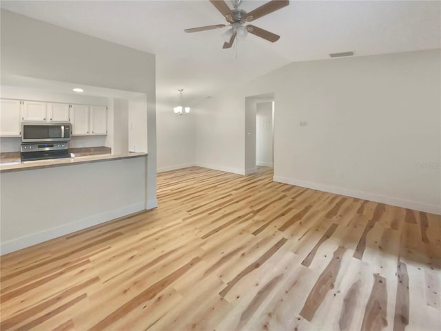 unfurnished living room featuring ceiling fan with notable chandelier, lofted ceiling, and light hardwood / wood-style flooring