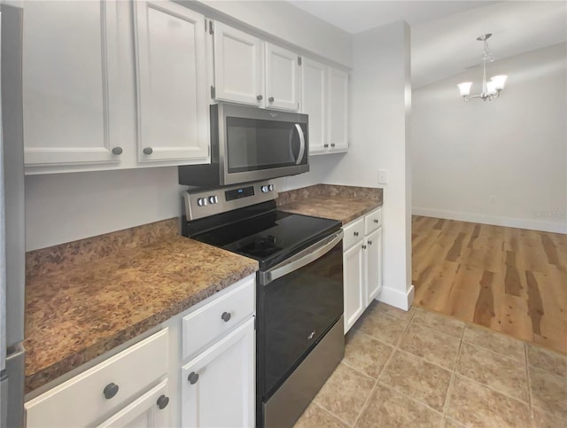 kitchen with pendant lighting, white cabinets, light wood-type flooring, appliances with stainless steel finishes, and a notable chandelier