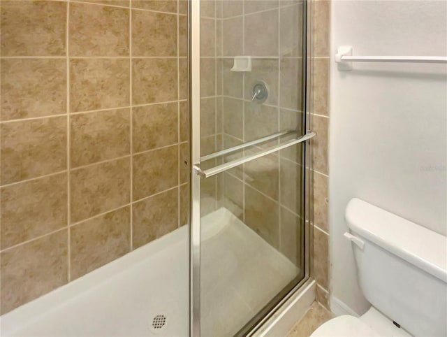 bathroom featuring toilet and a shower with shower door