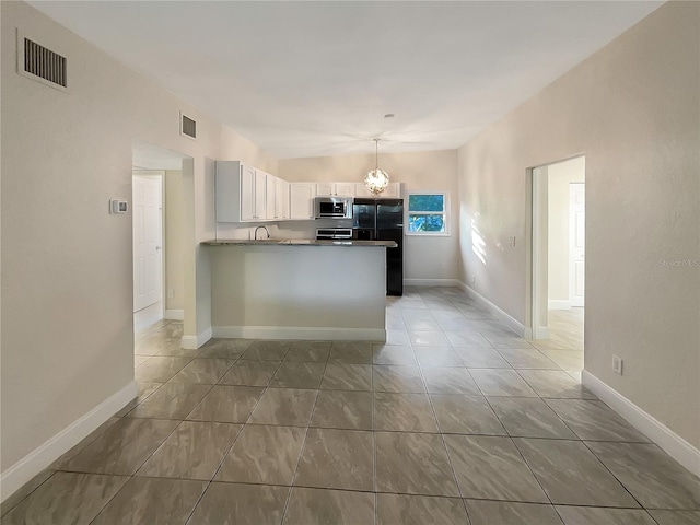 kitchen featuring pendant lighting, an inviting chandelier, white cabinets, black refrigerator, and kitchen peninsula