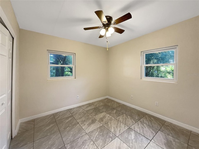 tiled empty room featuring plenty of natural light and ceiling fan