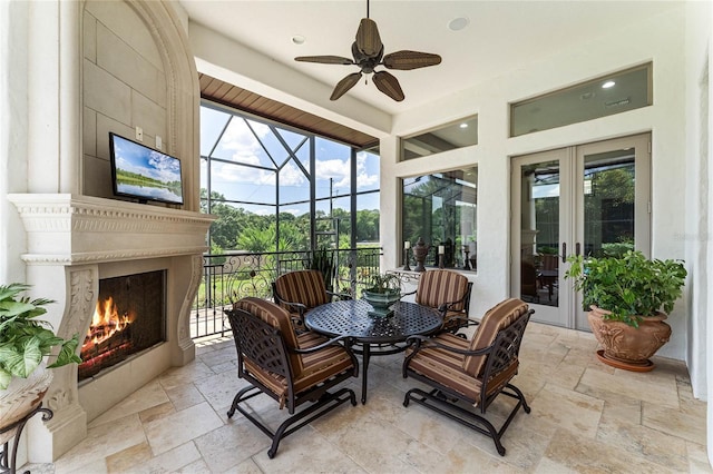 sunroom featuring ceiling fan and a fireplace