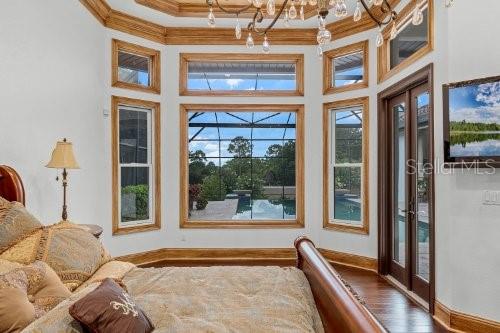 bedroom featuring multiple windows, ornamental molding, and a towering ceiling