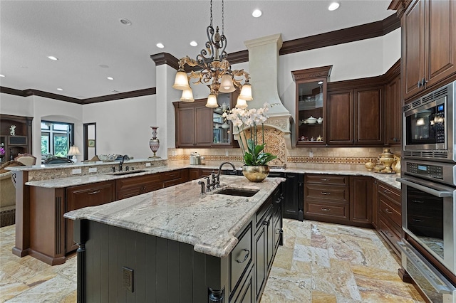 kitchen featuring stainless steel appliances, pendant lighting, sink, and a center island with sink