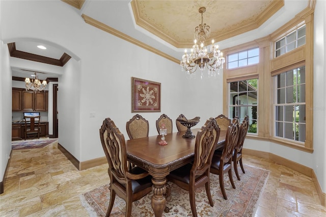 dining room featuring a chandelier, ornamental molding, and a raised ceiling