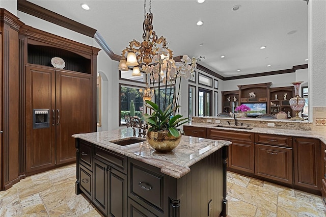 kitchen with ornamental molding, sink, a kitchen island with sink, and kitchen peninsula