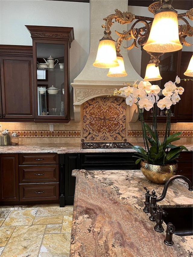 kitchen featuring dark brown cabinetry, sink, stainless steel gas cooktop, hanging light fixtures, and backsplash