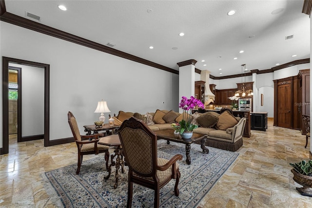 living room with crown molding, ornate columns, and a notable chandelier