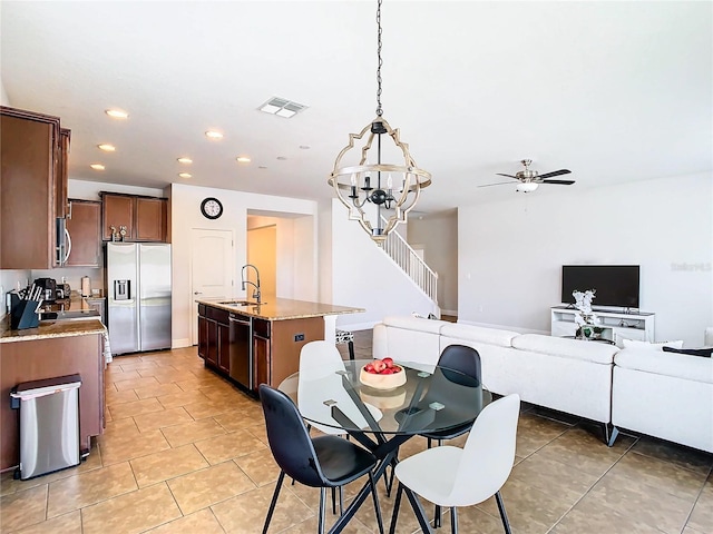 tiled dining space with sink and ceiling fan with notable chandelier