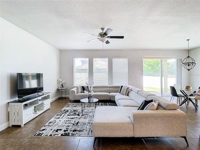 tiled living room featuring a textured ceiling, a wealth of natural light, and ceiling fan with notable chandelier