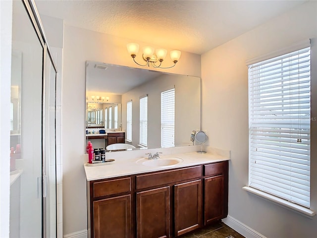 bathroom featuring vanity, a textured ceiling, and a shower with shower door