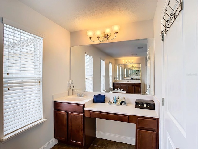 bathroom with vanity, a textured ceiling, a healthy amount of sunlight, and tile patterned flooring