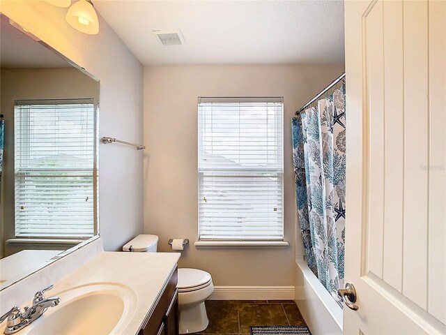 full bathroom with tile patterned floors, shower / bath combo with shower curtain, vanity, and toilet