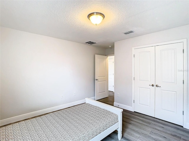 unfurnished bedroom featuring wood-type flooring, a textured ceiling, and a closet