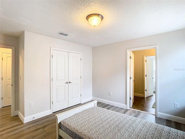 bedroom featuring a textured ceiling, dark wood-type flooring, and a closet