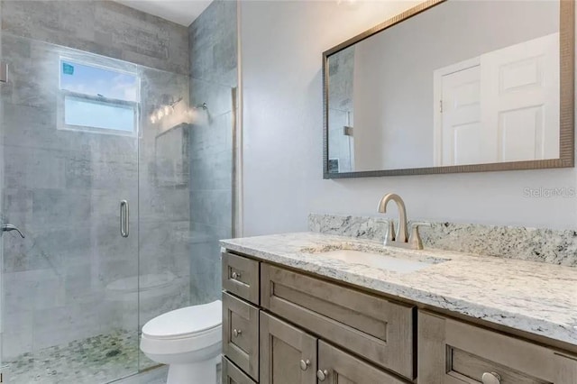 bathroom with a shower with door, vanity, and toilet