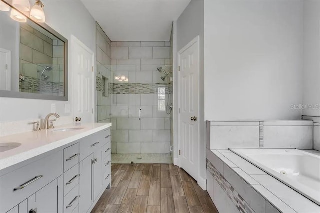 bathroom featuring dual sinks, vanity with extensive cabinet space, hardwood / wood-style floors, and shower with separate bathtub