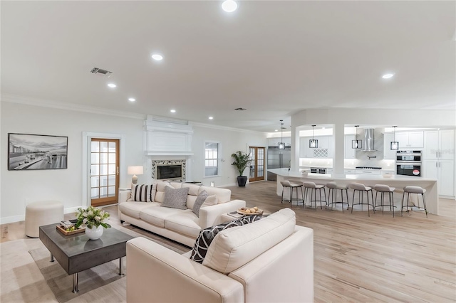 living room with light wood-type flooring, crown molding, and a premium fireplace