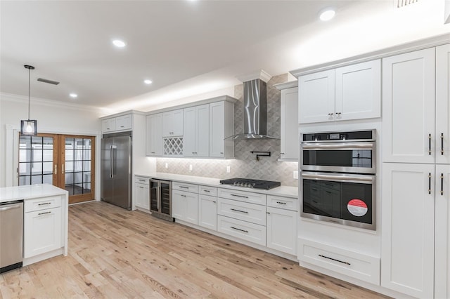 kitchen featuring appliances with stainless steel finishes, white cabinetry, beverage cooler, and wall chimney range hood