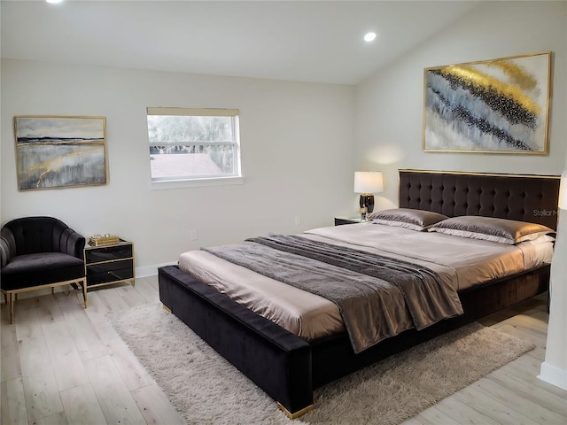 bedroom with light hardwood / wood-style floors and lofted ceiling