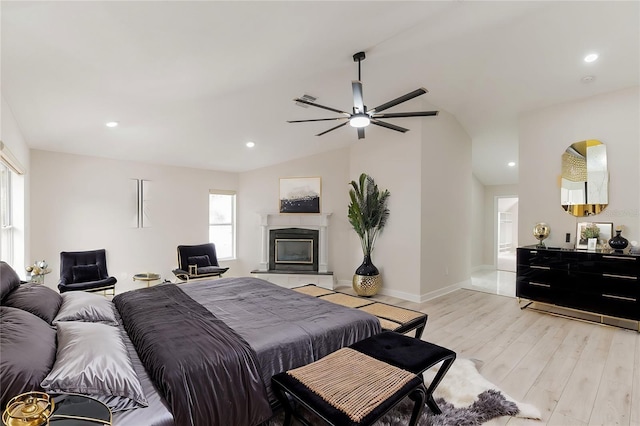 bedroom with a tile fireplace, light hardwood / wood-style flooring, ceiling fan, and lofted ceiling