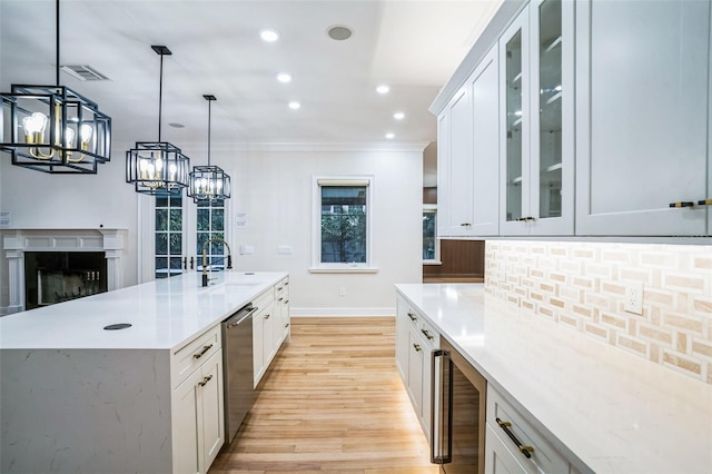 kitchen with light countertops, wine cooler, glass insert cabinets, and white cabinetry