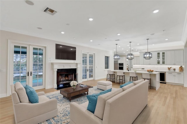 living area with beverage cooler, visible vents, ornamental molding, and french doors