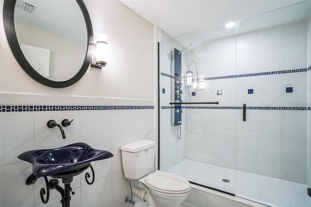 bathroom featuring a shower stall, visible vents, tile walls, and toilet