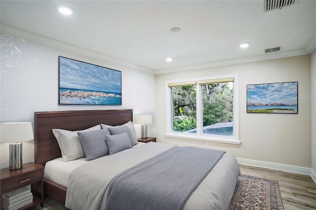 bedroom with baseboards, visible vents, wood finished floors, crown molding, and recessed lighting