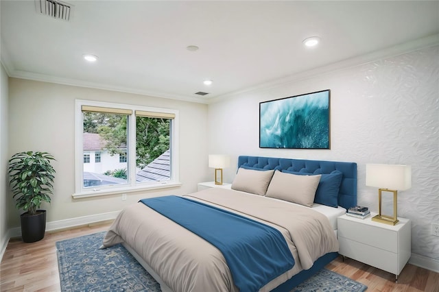 bedroom with light wood finished floors, baseboards, visible vents, and ornamental molding