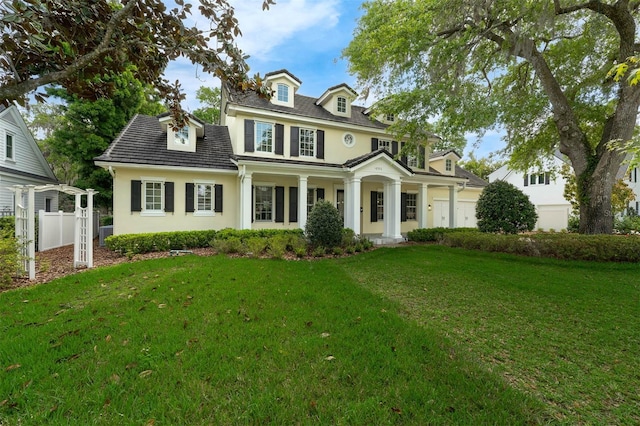 view of front of house with an attached garage, stucco siding, fence, and a front lawn