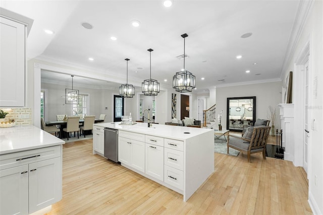 kitchen with light countertops, a chandelier, a sink, light wood-type flooring, and stainless steel dishwasher